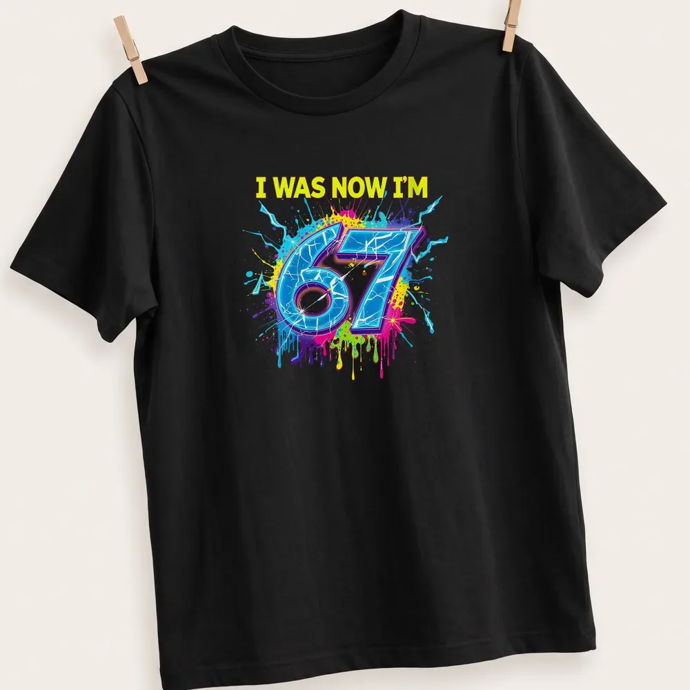 Colorful splatter design t-shirt with the text I WAS NOW I'M 67
