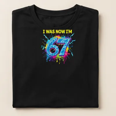 Colorful splatter design t-shirt with the text I WAS NOW I'M 67 — printed on a women's t-shirt