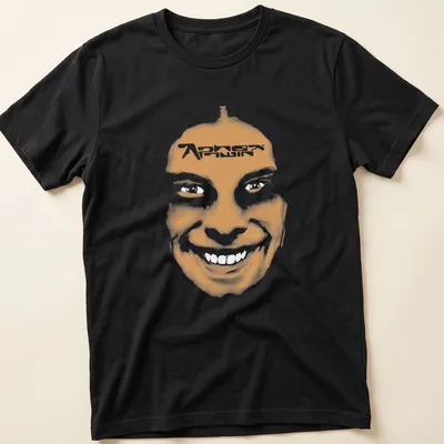 Minimalist t-shirt featuring a smiling face and 'Aphex Twin' text in orange and white.