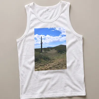 Cactus landscape illustration in green, brown, blue, and white on — printed on a tank top