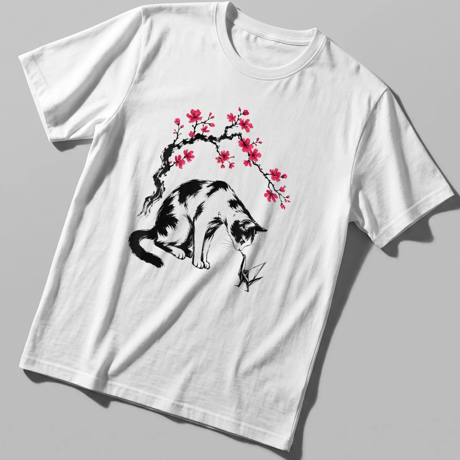 Illustration of a cat with an origami crane and cherry blossoms in black, pink, and white. — printed on a unisex t-shirt