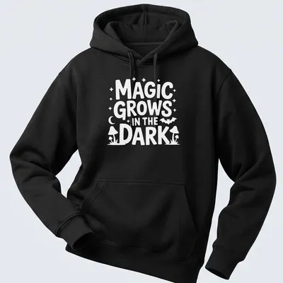 A dark themed t-shirt with the text 'Magic Grows In The Dark' surrounded by plant illustrations in black, green, and purple. — printed on a unisex hoodie