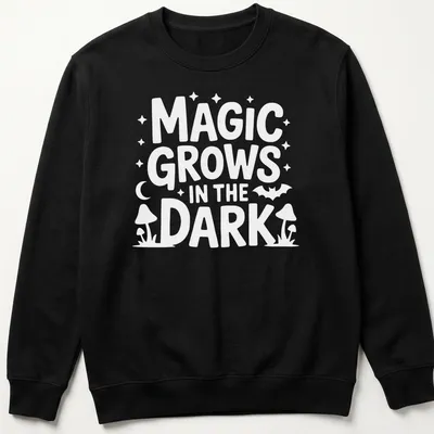 A dark themed t-shirt with the text 'Magic Grows In The Dark' surrounded by plant illustrations in black, green, and purple. — printed on a unisex sweatshirt