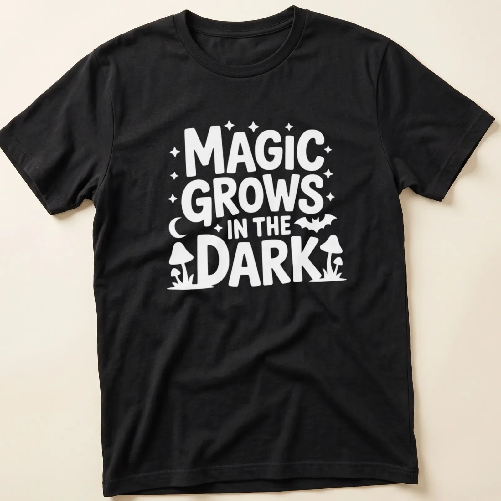 A dark themed t-shirt with the text 'Magic Grows In The Dark' surrounded by plant illustrations in black, green, and purple. — printed on a unisex t-shirt