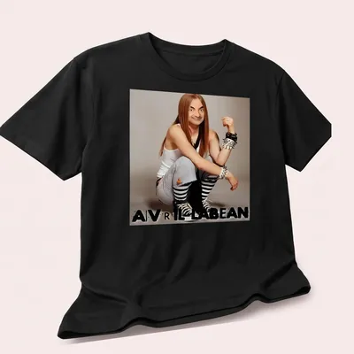 Humorous character resembling Avril Lavigne with a playful expression and bold text — printed on a unisex t-shirt (angled view)