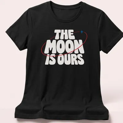 Bold typography T-shirt featuring the phrase 'THE MOON IS OURS' alongside a moon graphic — printed on a women's shirt