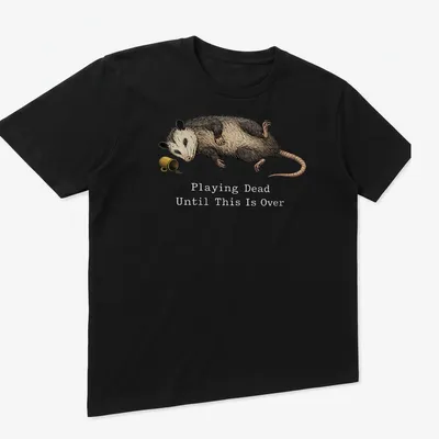 Realistic illustration of an opossum playing dead with humorous text — printed on a unisex t-shirt (angled view)