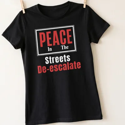 Bold typography t-shirt with the message PEACE In The Streets De-escalate in red and white. — printed on a women's shirt