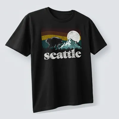 Retro bear graphic with Seattle text in pink, blue, yellow, and green — printed on a unisex t-shirt (angled view)