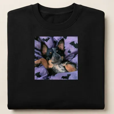Realistic depiction of a sleepy Cattle Dog on a purple bat-patterned blanket — printed on a unisex sweatshirt