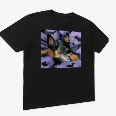 Realistic depiction of a sleepy Cattle Dog on a purple bat-patterned blanket — printed on a unisex t-shirt (angled view)