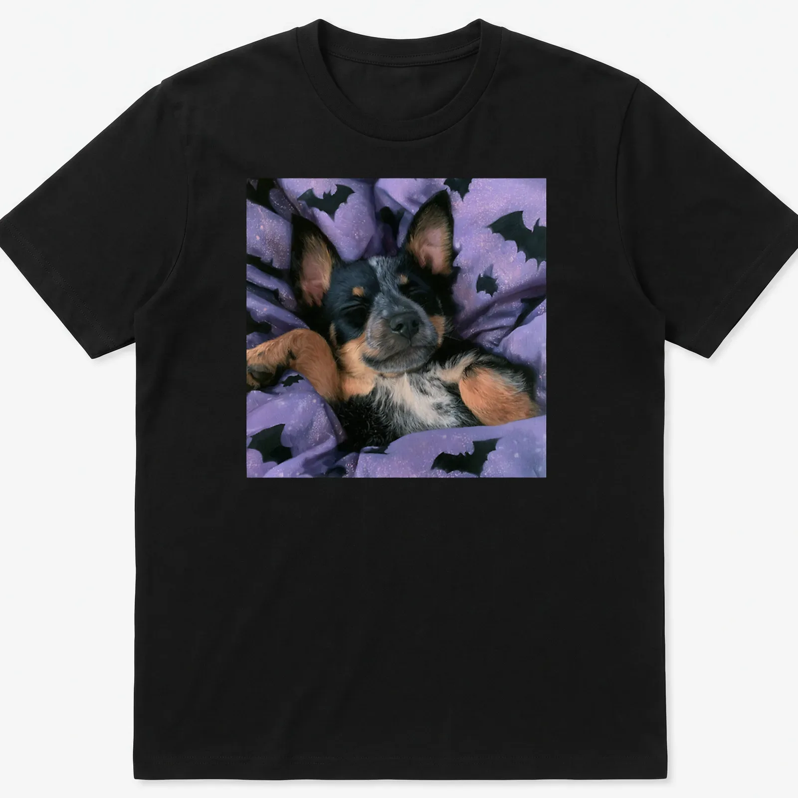 Realistic depiction of a sleepy Cattle Dog on a purple bat-patterned blanket — printed on a unisex t-shirt