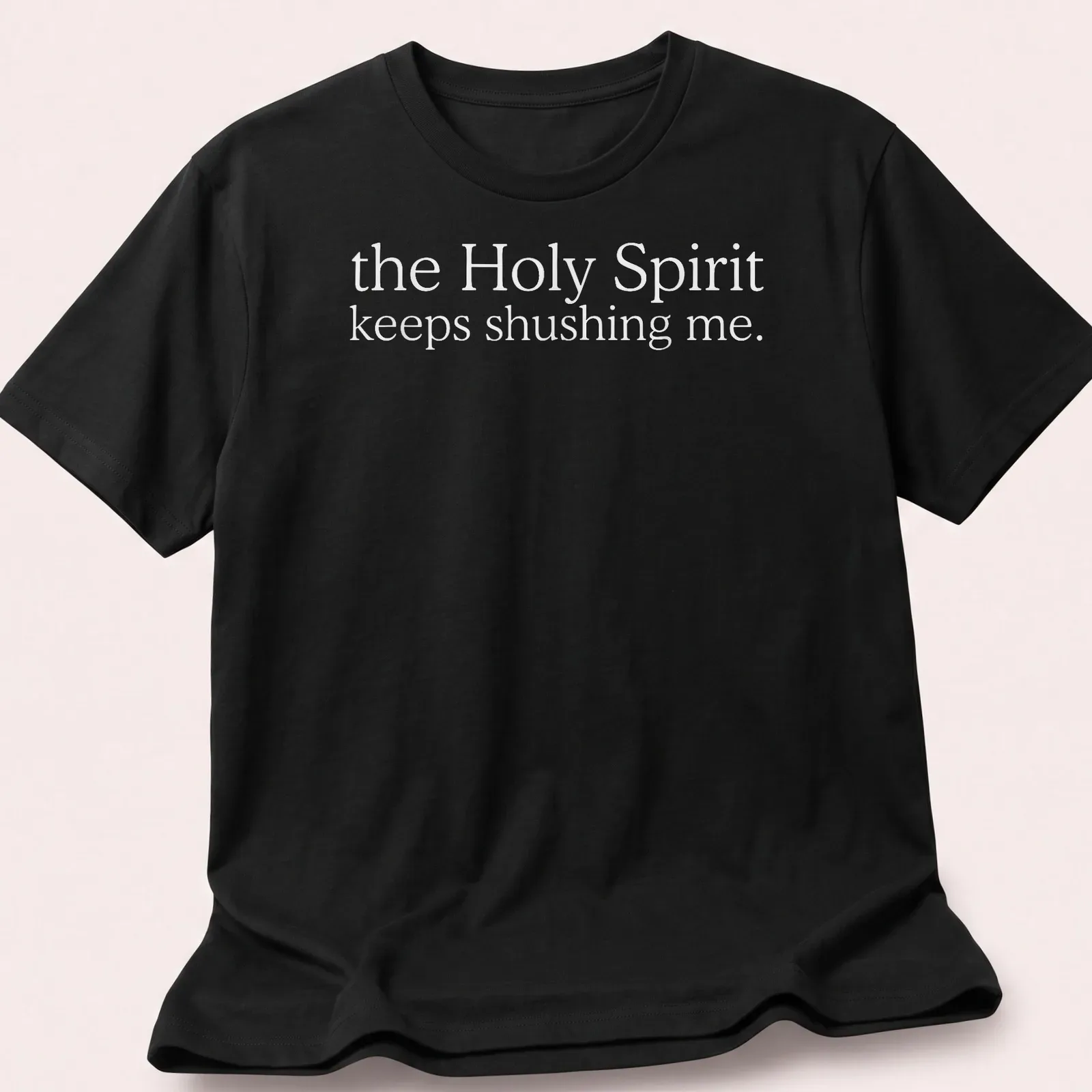 Simple white text reading 'the Holy Spirit keeps shushing me.' on a T-shirt. — printed on a unisex t-shirt
