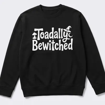 Cartoon toad graphic with playful text 'Toadally Bewitched' in green and black. — printed on a unisex sweatshirt