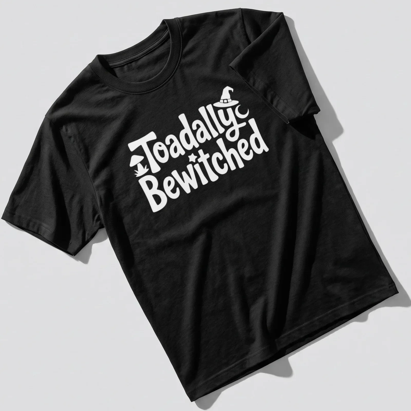 Cartoon toad graphic with playful text 'Toadally Bewitched' in green and black. — printed on a unisex t-shirt