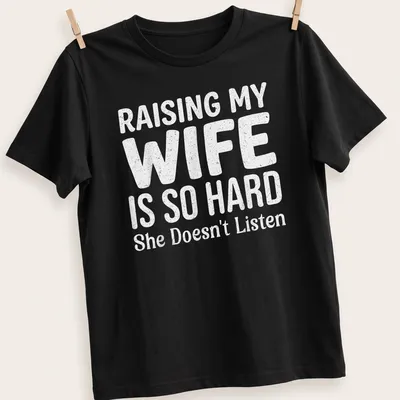 Bold playful typography on a light gray shirt about raising a wife.